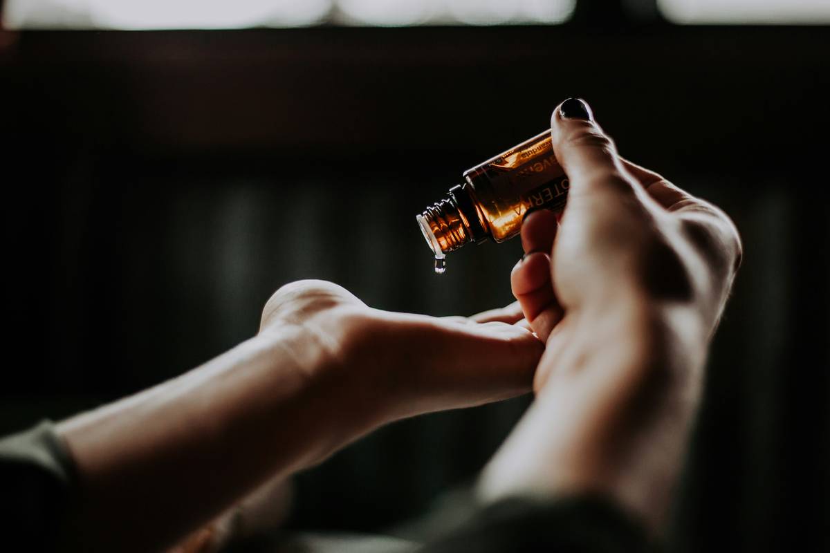 woman applying styling hair essence to damp hair for frizz control